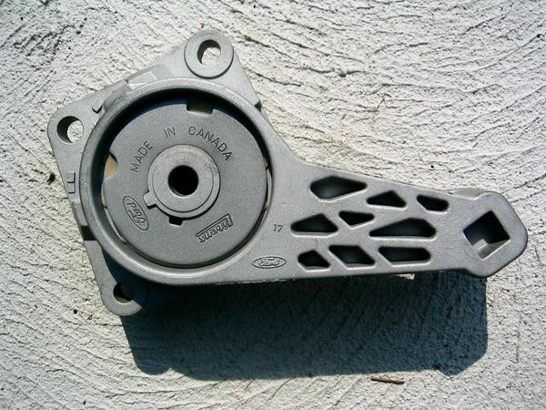 Photo of a Ford accessory drive tensioner bracket marked Made in Canada
