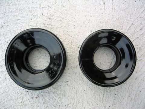2007 Ford Mustang - Photograph of two black pulley/cover parts with cast part-number markings, physical parts not a document.