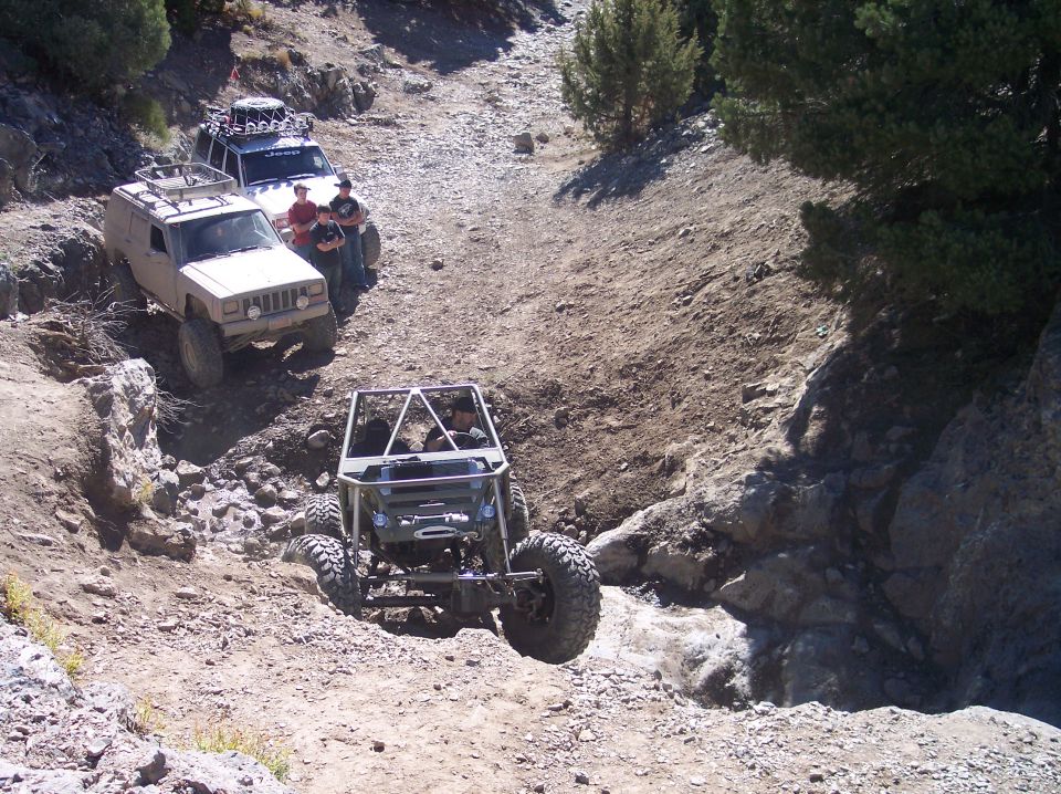 Two Jeeps and a custom off-road buggy on a rocky trail.