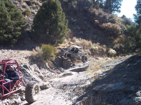 1995 Ford Bronco - Two off-road vehicles are navigating a rocky, uphill trail. The vehicle in the foreground is red and open-topped, while the vehicle behind…