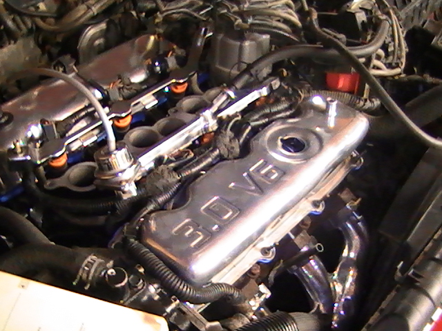 Close-up of a chrome "3.0 V6" engine cover in a Ford Probe engine bay.