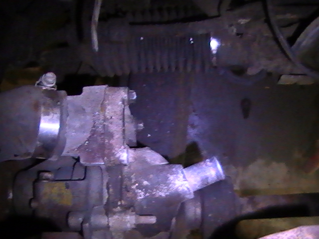 Close-up of a rusty metal vehicle part with a silver pipe.