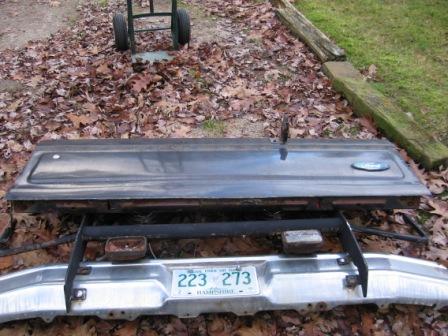 1993 Ford Bronco - A removed tailgate lies face-up on leaf-covered ground next to a chrome rear step bumper with a New Hampshire license plate reading 223 273…