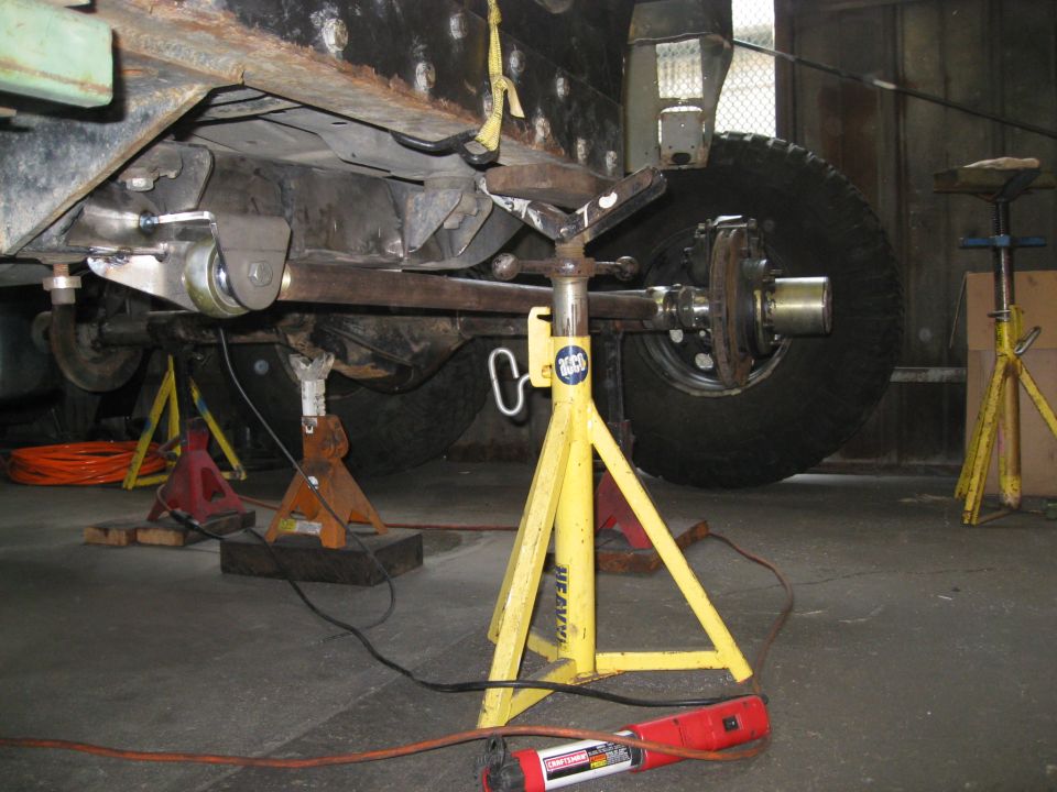 Undercarriage of a vehicle on jack stands in a garage.