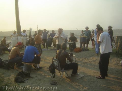 1968 Ford Mustang - photograph of a beach drum circle, not a technical document.