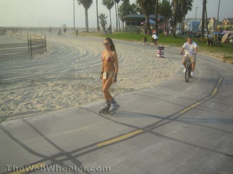 1968 Ford Mustang - A woman rollerblades along a beach path while a man cycles in the background.