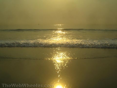 1968 Ford Mustang - The sun reflects on the wet sand and ocean waves during a hazy sunset at the beach.