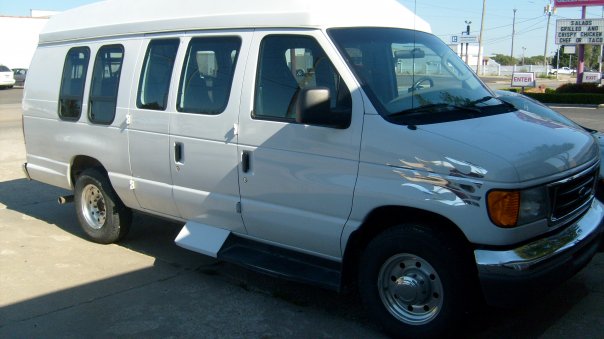 White 2006 Ford E250 van with flame decals on the fender, seen from the front 3/4 angle