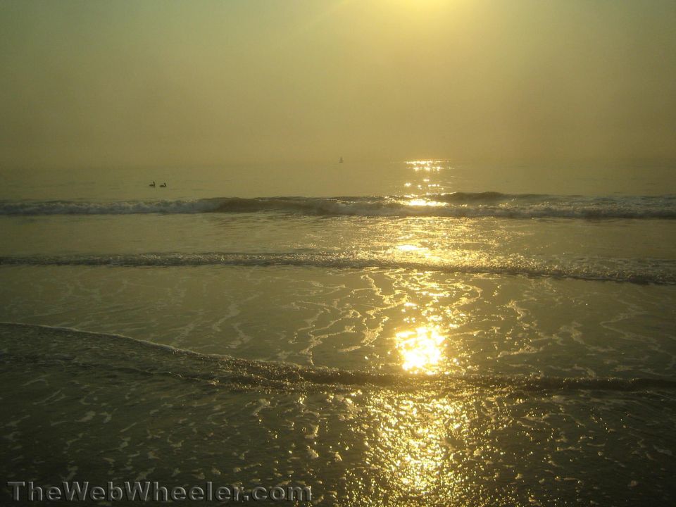 Beach scene with sun setting over the ocean