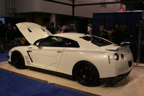 1998 Ford Crown Victoria - White Nissan GT-R on display with its hood open, custom graphics on the side.