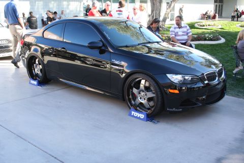 1998 Ford Crown Victoria - A black BMW M3 coupe is displayed at an outdoor event, resting on blue TOYO tire stands.