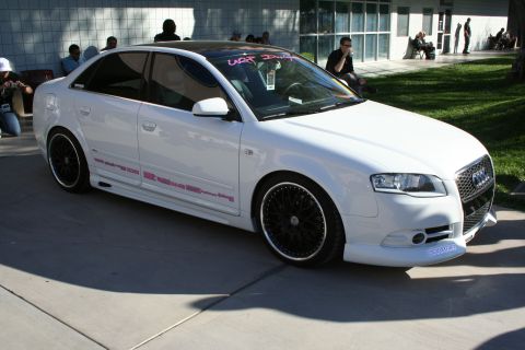 1998 Ford Crown Victoria - A white Audi sedan is parked outside a building with people in the background.