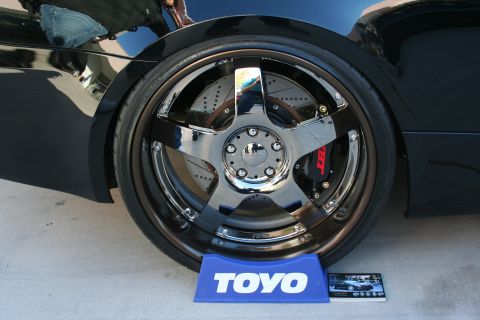 1998 Ford Crown Victoria - A close-up of a custom chrome wheel and red brake caliper on a black vehicle.