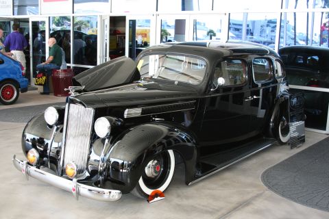 1998 Ford Crown Victoria - A black sedan with a distinctive chrome grille and whitewall tires is displayed indoors.