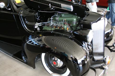 1998 Ford Crown Victoria - Close-up of a vintage black car's engine bay and front fender with whitewall tires.