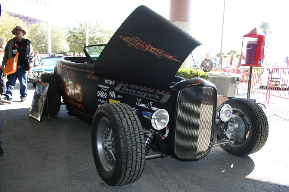 Black hot rod with hood open, showing pinstriping and various sponsor decals on the side