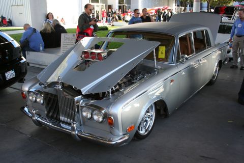 1998 Ford Crown Victoria - A heavily modified silver Rolls-Royce is displayed with its hood open, revealing a custom engine setup.