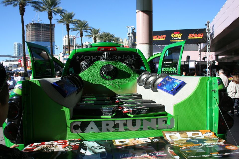 Green pickup truck bed with multiple subwoofers and amplifiers, "CARTUNE" text visible