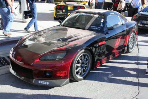 1998 Ford Crown Victoria - A modified sports car with racing graphics is parked outdoors, with other vehicles and people in the background.
