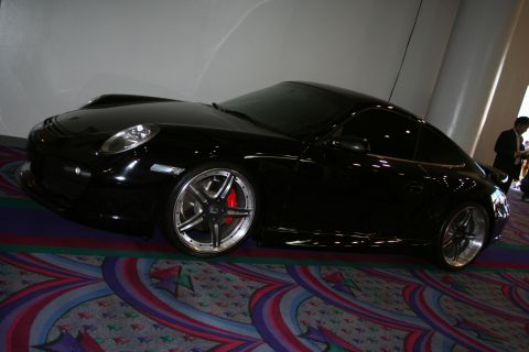 1998 Ford Crown Victoria - A black sports car with aftermarket wheels is parked indoors on a patterned carpet.