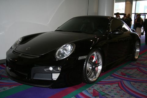 1998 Ford Crown Victoria - A black Porsche 911 is displayed indoors on a patterned carpet, custom wheels and prominent red brake calipers.