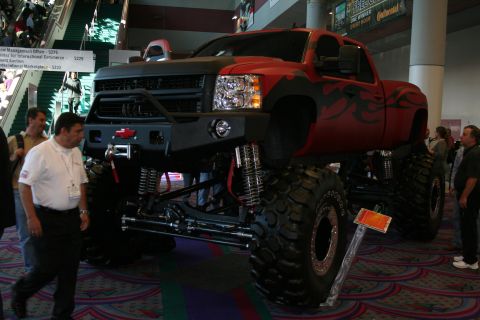 1998 Ford Crown Victoria - A heavily modified pickup truck is displayed indoors with people around.