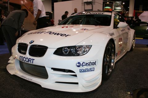 1998 Ford Crown Victoria - A white BMW race car is displayed indoors, prominent sponsor decals and racing modifications.