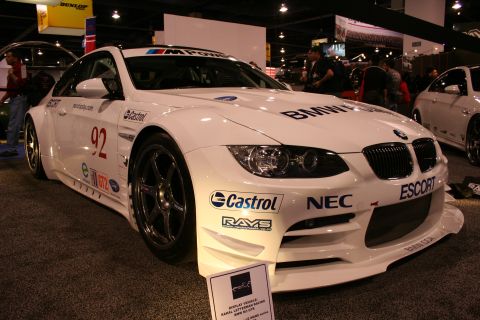 1998 Ford Crown Victoria - A white BMW M3 GTR race car is displayed indoors with various sponsor decals and racing modifications.