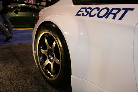 1998 Ford Crown Victoria - A white vehicle with 'ESCORT' branding is shown from the side, a racing wheel and tire.