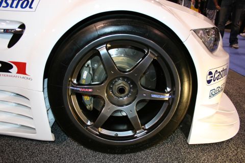 1998 Ford Crown Victoria - Close-up of a white race car's front wheel, fender, and aerodynamic components.
