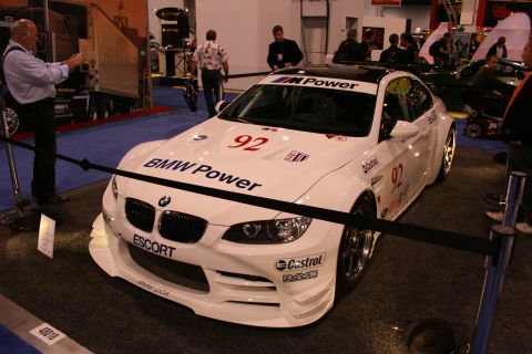 1998 Ford Crown Victoria - A white BMW M3 race car is displayed indoors with various sponsor decals and racing numbers.