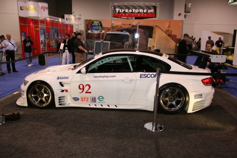 1998 Ford Crown Victoria - A white racing car with racing decals and a spoiler is displayed indoors.