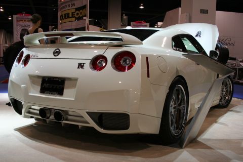 1998 Ford Crown Victoria - A white Nissan GT-R is displayed at an auto show, its rear design and custom wheels.