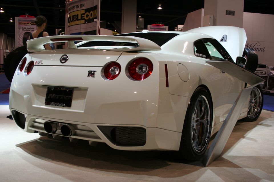 White Nissan GT-R with spoiler and dual exhaust pipes, seen from the rear