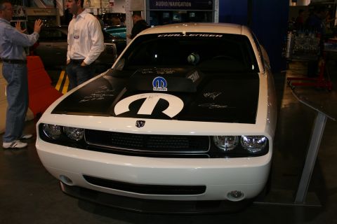 1998 Ford Crown Victoria - A white Dodge Challenger is displayed indoors with a prominent Mopar logo and signatures on its hood.