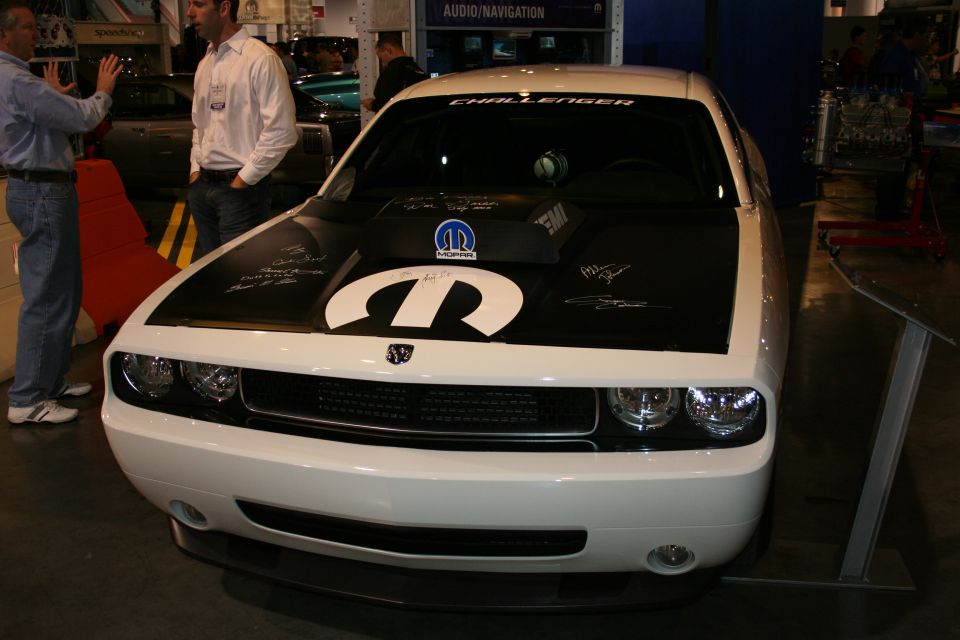 White Dodge Challenger with black hood Mopar logo and signatures. Text on windshield reads CHALLENGER