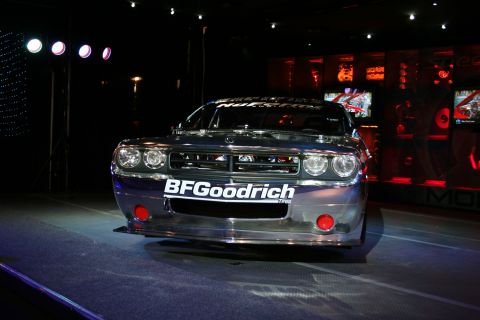 1998 Ford Crown Victoria - A highly polished Dodge Challenger SRT8 is displayed under stage lights with screens in the background.