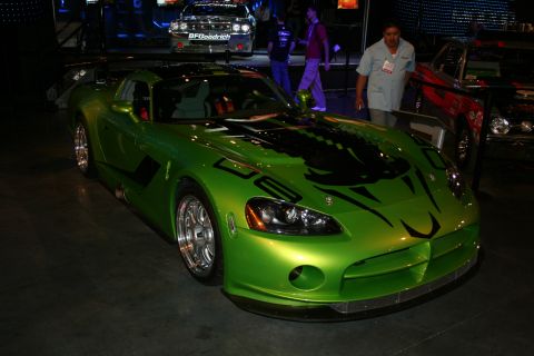 1998 Ford Crown Victoria - A bright green Dodge Viper with distinctive black racing graphics on its hood is displayed indoors, with other vehicles visible in the back…