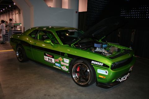 1998 Ford Crown Victoria - A bright green Dodge Challenger is displayed with its hood up, revealing the engine and various sponsor decals on its body.