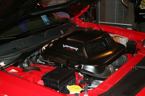 1998 Ford Crown Victoria - Close-up of a black engine cover with "Viper" branding, part of a red vehicle's engine bay.