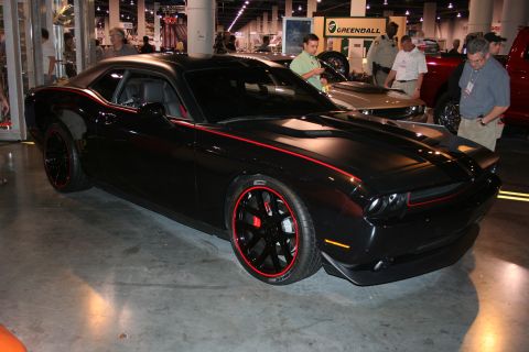 1998 Ford Crown Victoria - A black Dodge Challenger with red accents on the body and wheels is displayed indoors.