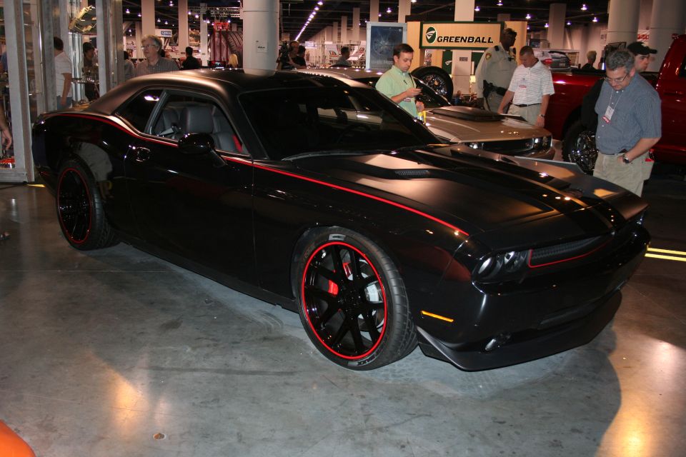 Black Dodge Challenger with red pinstriping and wheels, parked indoors