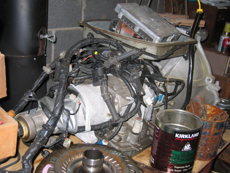Engine and transmission components with visible wiring harnesses and a metal casing