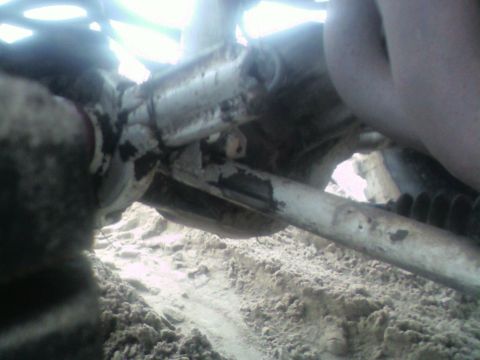 1992 Ford F-350 - Close-up view of a vehicle's undercarriage, showing mechanical parts and sandy terrain.