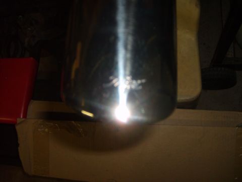 1993 Ford Crown Victoria - A close-up view of a chrome exhaust pipe, showing scratches and a strong light reflection.