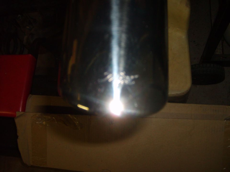 Chrome exhaust pipe with visible scratches and a bright light reflection