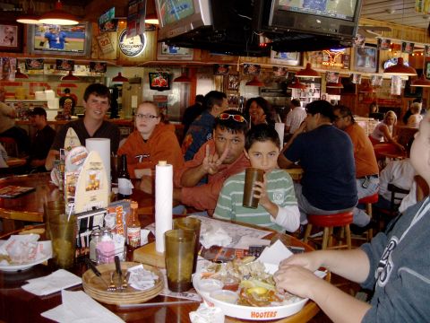 1984 Ford Bronco - A group of people are gathered at tables inside a Hooters restaurant.
