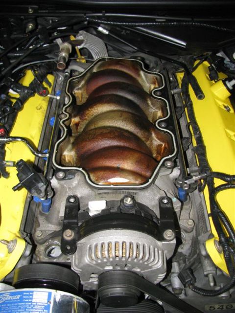 2003 Mercury Marauder - Close-up view of an engine's intake manifold and alternator, bright yellow valve covers.