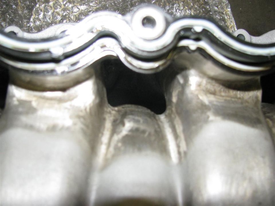 Engine intake manifold with gasket, showing internal ports and wear