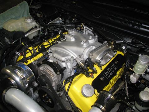 2003 Mercury Marauder - Engine bay detail with yellow valve covers and a silver intake manifold, a turbocharger and alternator.